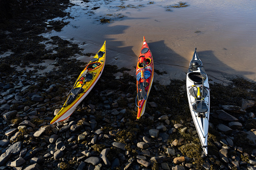 A shot of three colourful kayaks resting on the waters edge in Dumfries, Scotland.