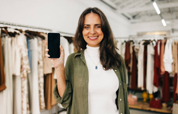 istock Small business owner holding up a smartphone, recommending using mobile apps 1482770302