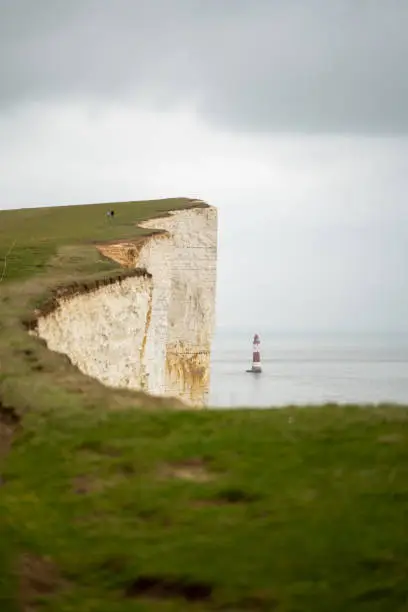 Landscape scene Seven sisters beach and cliffs in southern England. Small lighthouse in the sea with white cliffs and Road