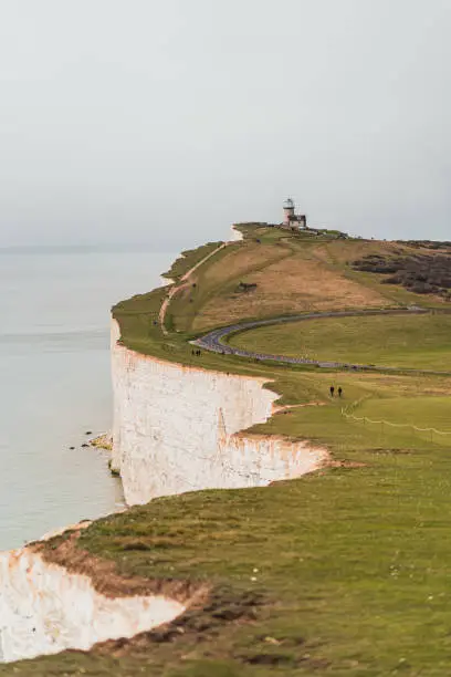 Landscape scene Seven sisters beach and cliffs in southern England. Small lighthouse in the sea with white cliffs and Road
