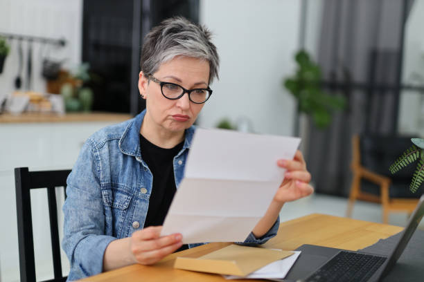 istock Upset senior woman reading mail or bill at table. 1482775537