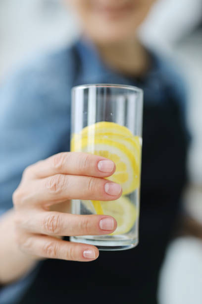 istock Close-up, glass with lemon water in hand. 1482775556