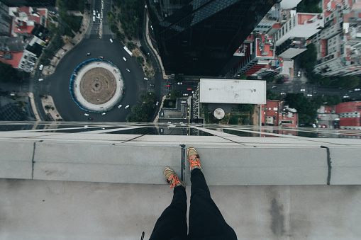 Una persona mirando abajo desde la azotea de un edificio alto se ven solo sus pies está a punto de caer provoca vértigo