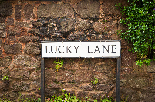 Lucky Lane street sign set against red stone wall in Exeter, England, UK.
