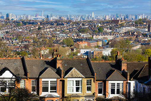 Panoramic view across the city of London, taking in huge residential districts, with the ultra modern architecture of the skyscrapers of downtown visible on the horizon.