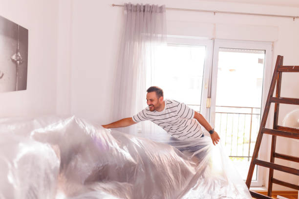 Man protecting furniture before home painting stock photo