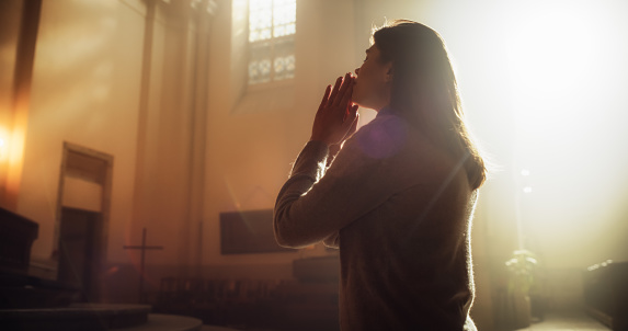 Side View: Christian Woman Getting on her Knees in Front of Altar and Starting to Pray in Church. Devoted Parishioner Seeks Guidance From Faith and Spirituality. Religious Believer in Power of God