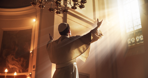 El Papa levanta sus manos en un gesto de bendición universal, ya que está siendo iluminado por la guía de Dios. Él está levantando sus manos hacia el cielo como una señal de total devoción al Señor photo