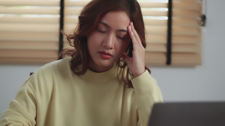 Stressed Asian woman with bills from credit card full table Calculate home financial budget