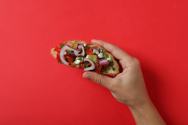 istock Female hand holds bruschetta on red background 1482787869