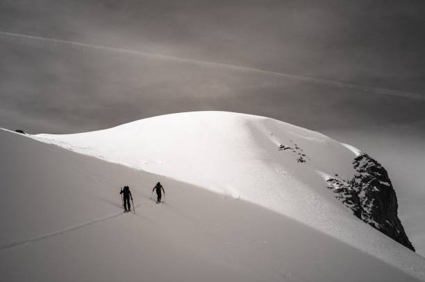 istock Two skiers hiking on a snowy mountain under a dark cloudy sky 1482788797