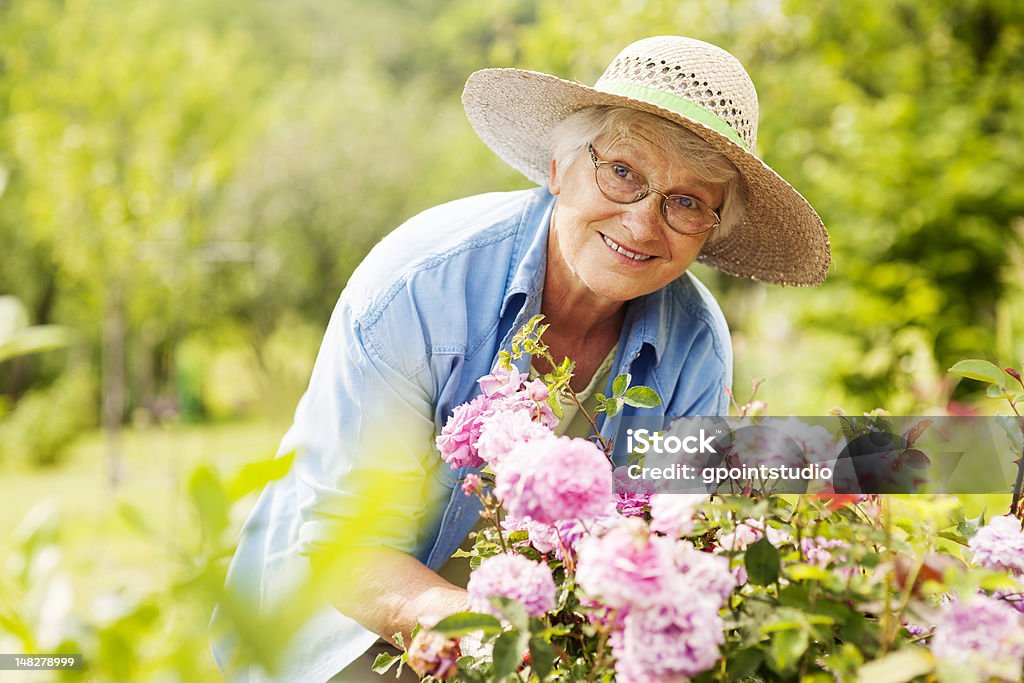 Senior mujer con flores en el jardín - Foto de stock de Tercera edad libre de derechos