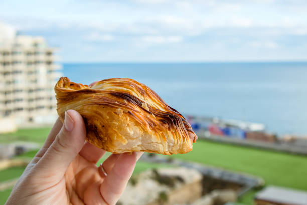 パスティッツィまたはパスティッツィと呼ばれる地元のマルタ料理。青い空と海の背景にマルタ・スリーマ市とダイヤモンド型の小さなパイを持つ人。 - diamond shaped ストックフォトと画像