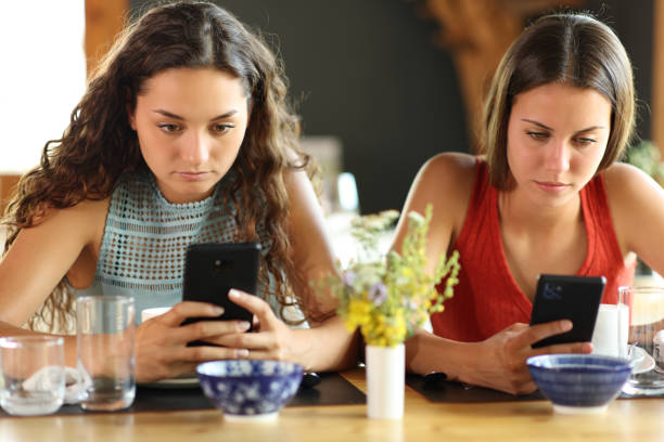 istock Friends in a restaurant ignoring each other using phones 1482792335
