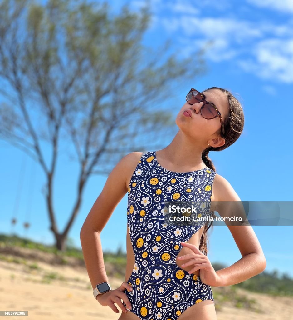 Beautiful girl blowing kisses Beautiful girl in a swimsuit on the beach sand blowing kisses 12-13 Years Stock Photo