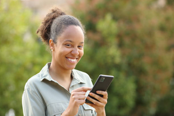 istock Happy black woman holding phone looking at camera 1482792399