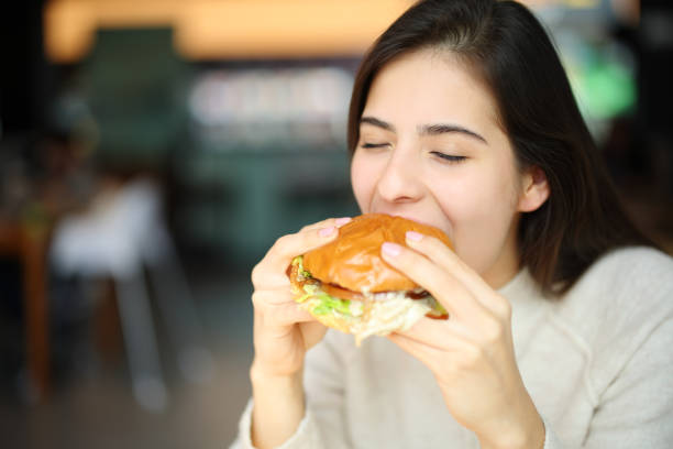 istock Woman eating burger in a restaurant 1482792425