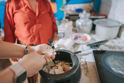 Asian Chinese female tourist learning cooking local traditional food from Bhutanese senior woman in kitchen