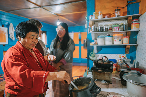 Bhutanese senior woman cooking, preparing dinner for her guest