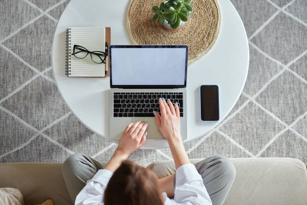 istock Mockup white screen laptop woman using computer sitting on sofa at home, top view 1482797082