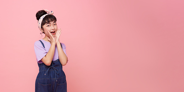 happy little asian girl shout story or making announcement isolated on pink copy space background.