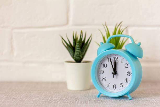 istock A blue alarm clock on a table with a gray tablecloth. 1482798373