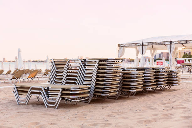 istock Empty sun loungers stacked on a sandy beach by the sea 1482798539
