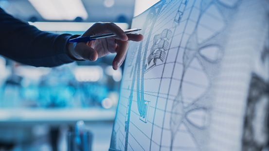 Close Up of a Desktop Computer Monitor Screen with 3D CAD Software with Prototype Jet Engine Project. Specialist Discussing Work, His Hand Visible In Front of the Screen.