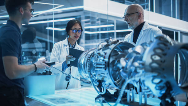istock Diverse Multiethnic Team of Industrial Engineers Gathered Around a Table With a Prototype Turbine Engine. Scientists Use Tablet Computer to Research, Develop and Program the Futuristic Motor. 1482799990