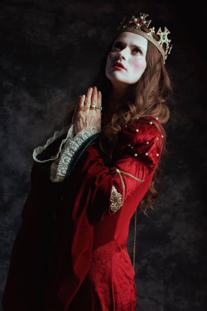 istock medieval queen in red dress with crown praying 1482801550