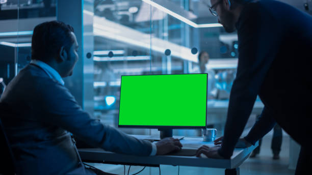 zwei entwickler, die an einem computer mit greenscreen-mock-up-display arbeiten. wissenschaftliches labor, engineering research center mit spezialisten, die im hintergrund an der entwicklung von turbinentriebwerken arbeiten. - computer lab green office computer stock-fotos und bilder