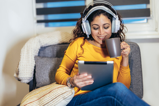 Woman wearing headset relaxing at home with music, enjoying leisure time.