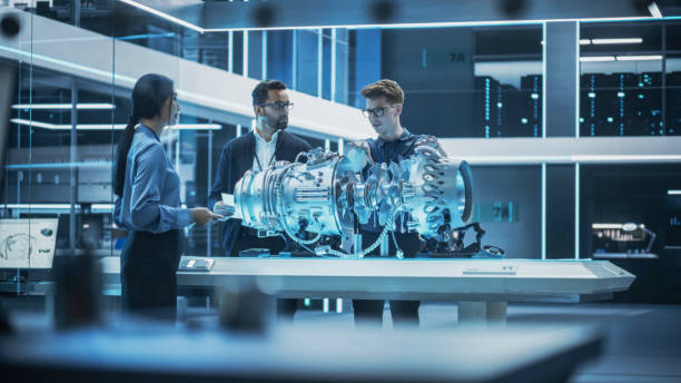istock Young Team of Engineers, Project Manager and Machinery Operators Collaborate on a New Type of a Gas Turbine Engine, Standing with Tablet and Laptop Computers in Scientific Technology Lab. High Angle. 1482802715