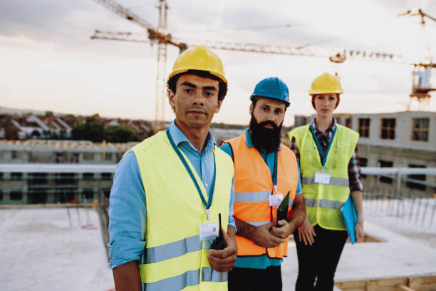 istock Construction employees looking at camera, while standing on the top of the building 1482802945