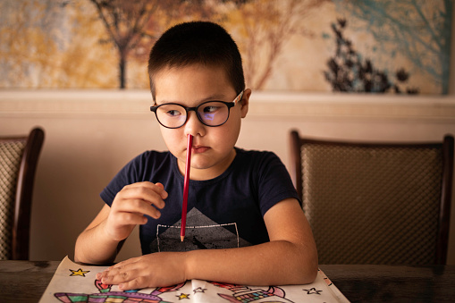 A bored little boy student inserted a pencil into his nose. The concept of ADHD