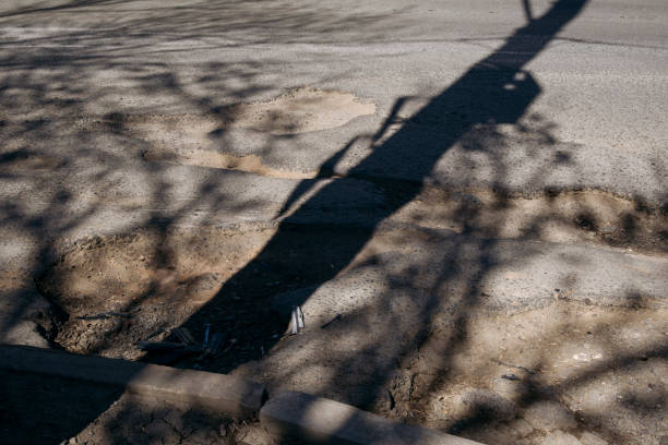 istock A highway with large pits and shadows from trees. 1482808535