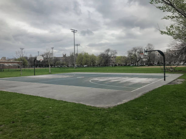 Empty basketball court in large park with overcast sky Empty basketball court in large park with overcast sky in urban Chicago asphalt basketball court stock pictures, royalty-free photos & images