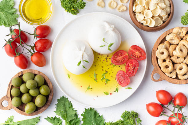 puglian cuisine, the most famous ingredients of the south italy: burrata cheese, olive oil, homemade orecchiette pasta, taralli, tomatoes and turnip tops or cima di rapa, pepperoncini. puglia, bari - mozzarella cheese italy tomato imagens e fotografias de stock