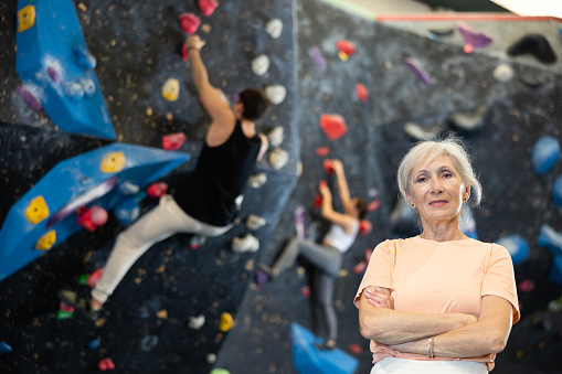 Senior female climber getting ready to climb wall in gym