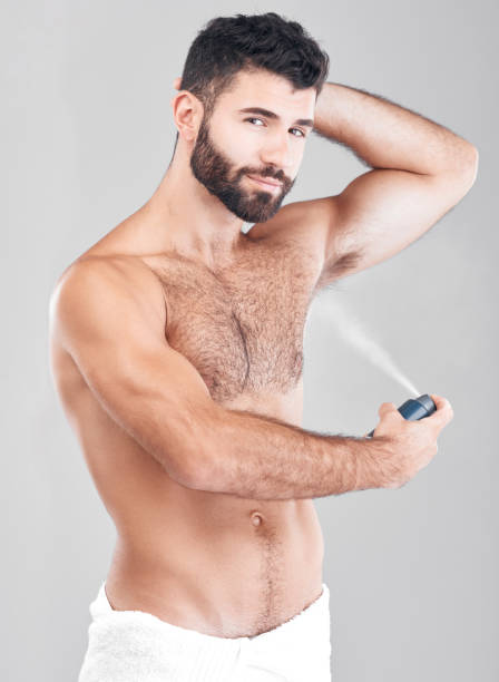 istock Portrait, deodorant and man spray armpit for hygiene, fresh scent and grooming isolated on a gray studio background. Cosmetics, wellness and young male model with perfume, fragrance or antiperspirant 1482811109