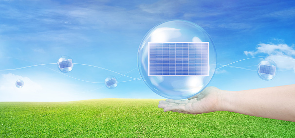 Solar panel in a bubble floating on hand Floating in the air, with grass and sky in the background. Solar energy concept. Clean energy.
