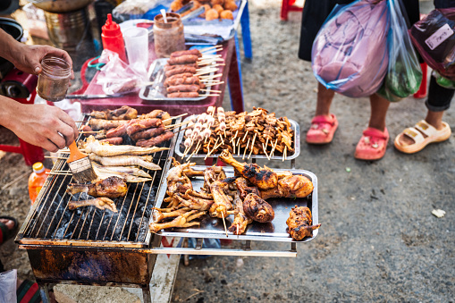 man peparing poultry barbecue and skewers on street market in Bac Ha, Vietnam
