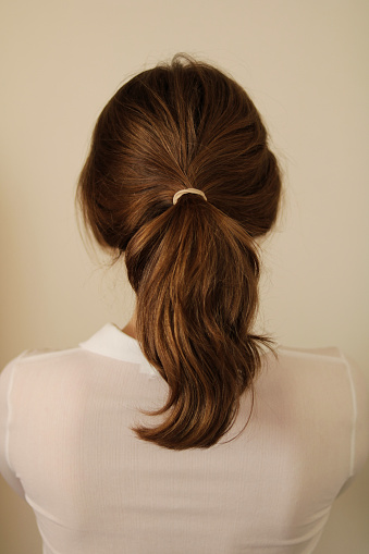Young woman with thick, dark blonde hair pulled back into a wavy ponytail