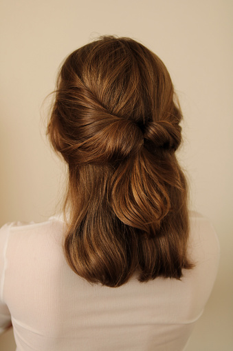 Twisted half-up ponytail hairstyle. Casual hairstyle. White shirt. Back view of a hairstyle. No face.