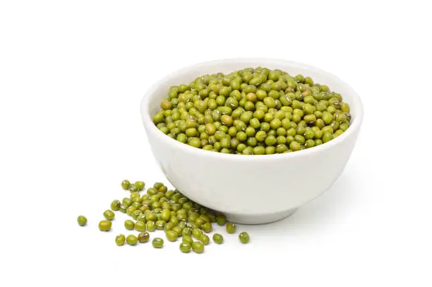 Mung bean (Vigna radiata) seeds in a white bowl isolated on white background.