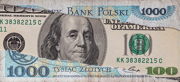 100 dollar banknote through torn 1000 Polish zloty banknote for design purpose
