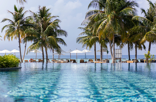 Swimming pool with patterned tiles in a hotel in the Maldives, against the backdrop of a tropical beach.