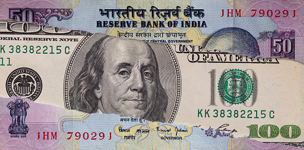 100 dollar banknote through torn Indian rupee banknote for design purpose