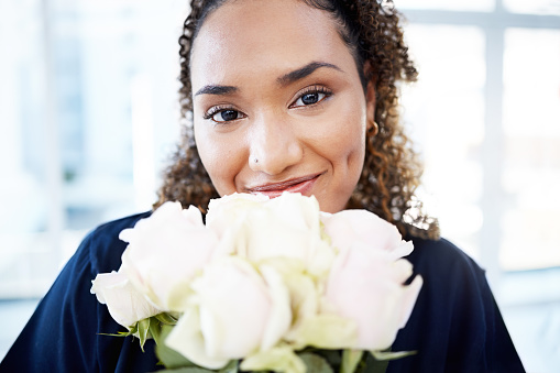 Brunette young woman with a large bouquet of flowers on golden shiny paper background.