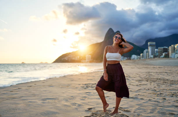 full body portrait young brazilian woman posing and smiling happy on Ipanema beach in Rio de Janeiro at beautiful sunset stock photo